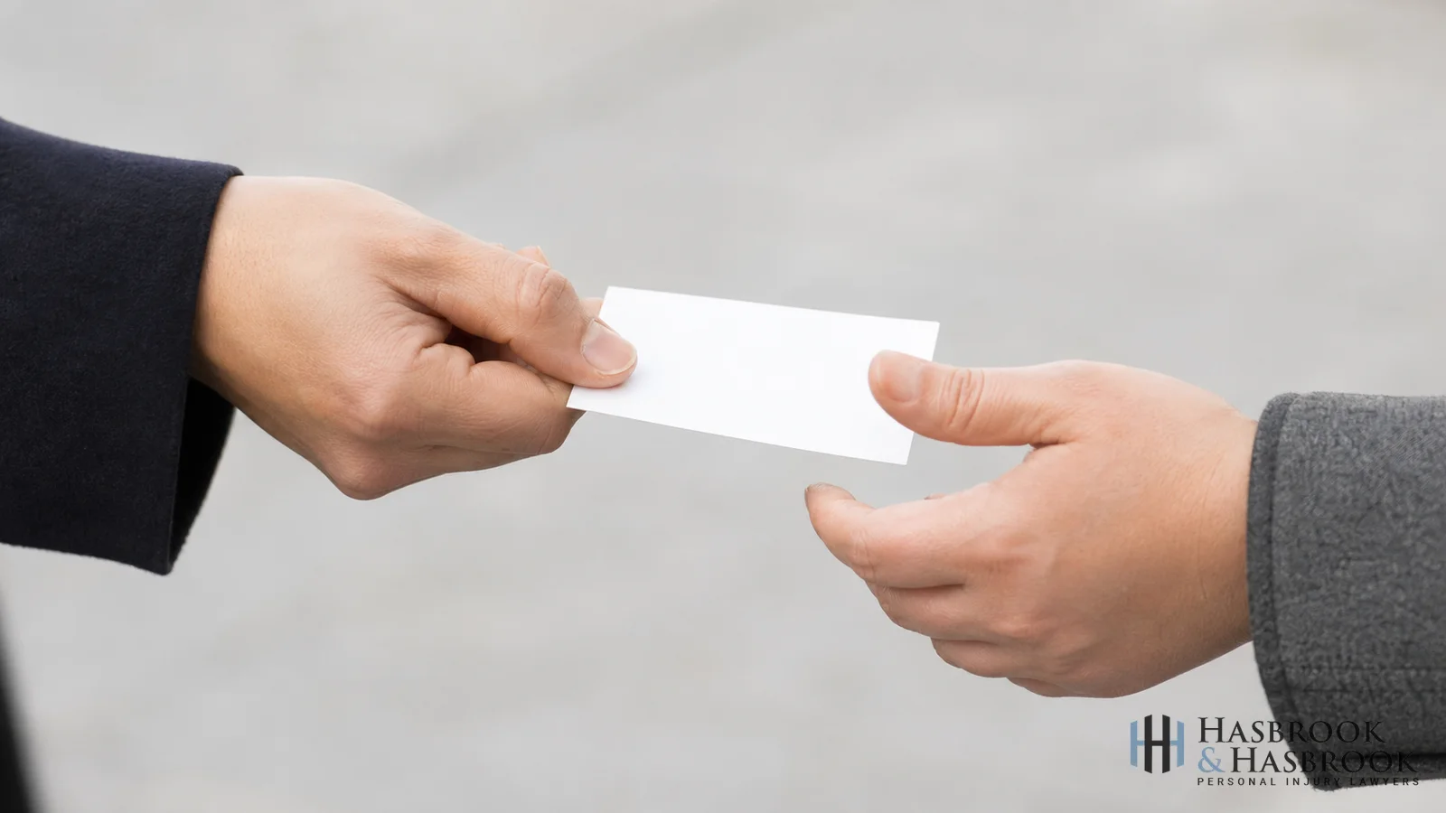 Hand passing a blank business card to another hand outdoors &mdash; illustrating witness contact collection at a slip-and-fall scene